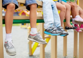 Kids sitting on playground equipment with feet hanging down
